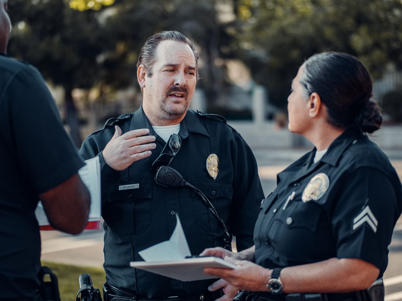 Home Three police officers engage in conversation outdoors, showcasing teamwork.